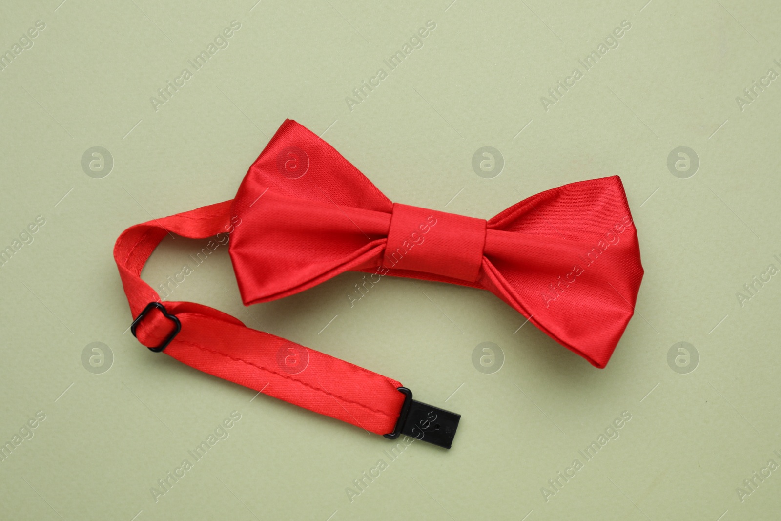 Photo of Stylish red bow tie on pale green background, top view