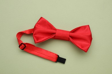 Photo of Stylish red bow tie on pale green background, top view
