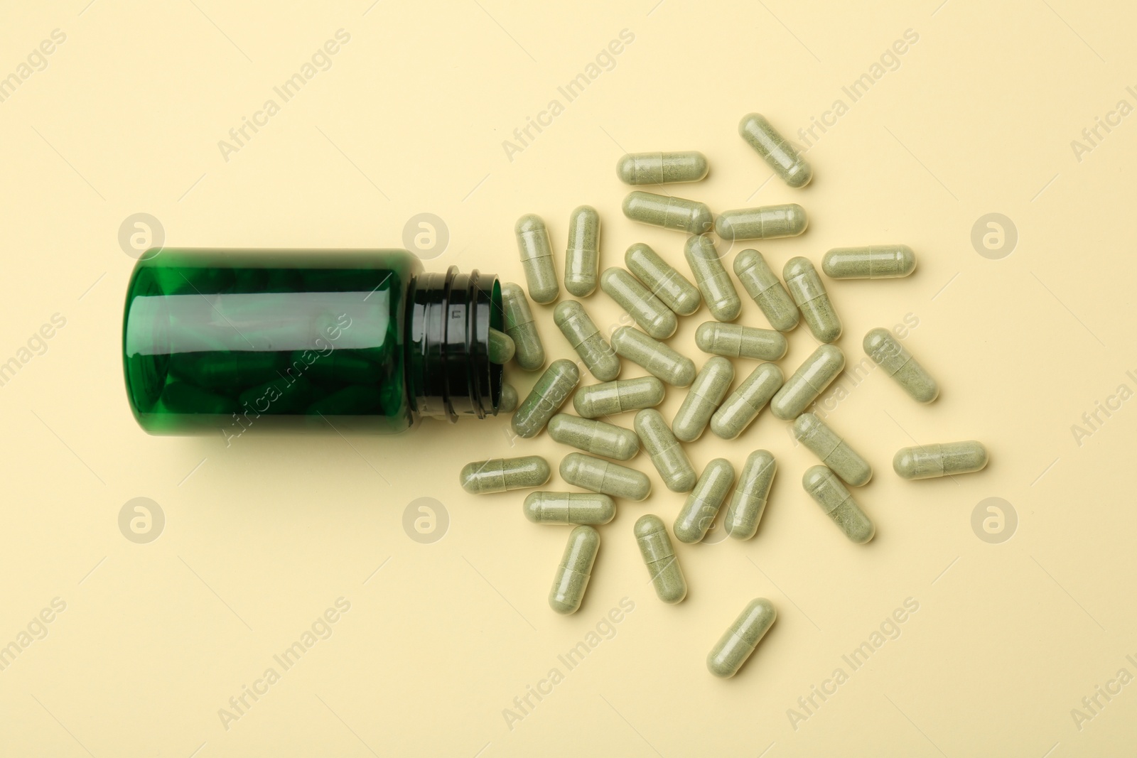 Photo of Vitamin pills and bottle on beige background, top view