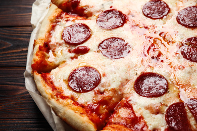 Photo of Hot delicious pepperoni pizza on wooden table, closeup