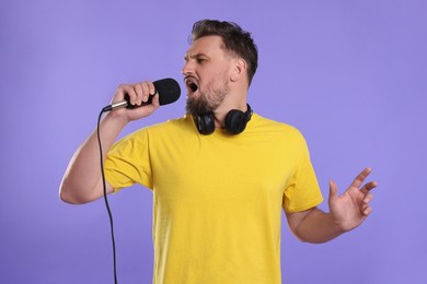 Photo of Handsome man with microphone singing on violet background