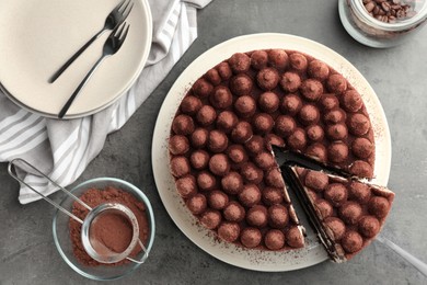 Photo of Delicious tiramisu cake with cocoa powder and server on grey table, flat lay