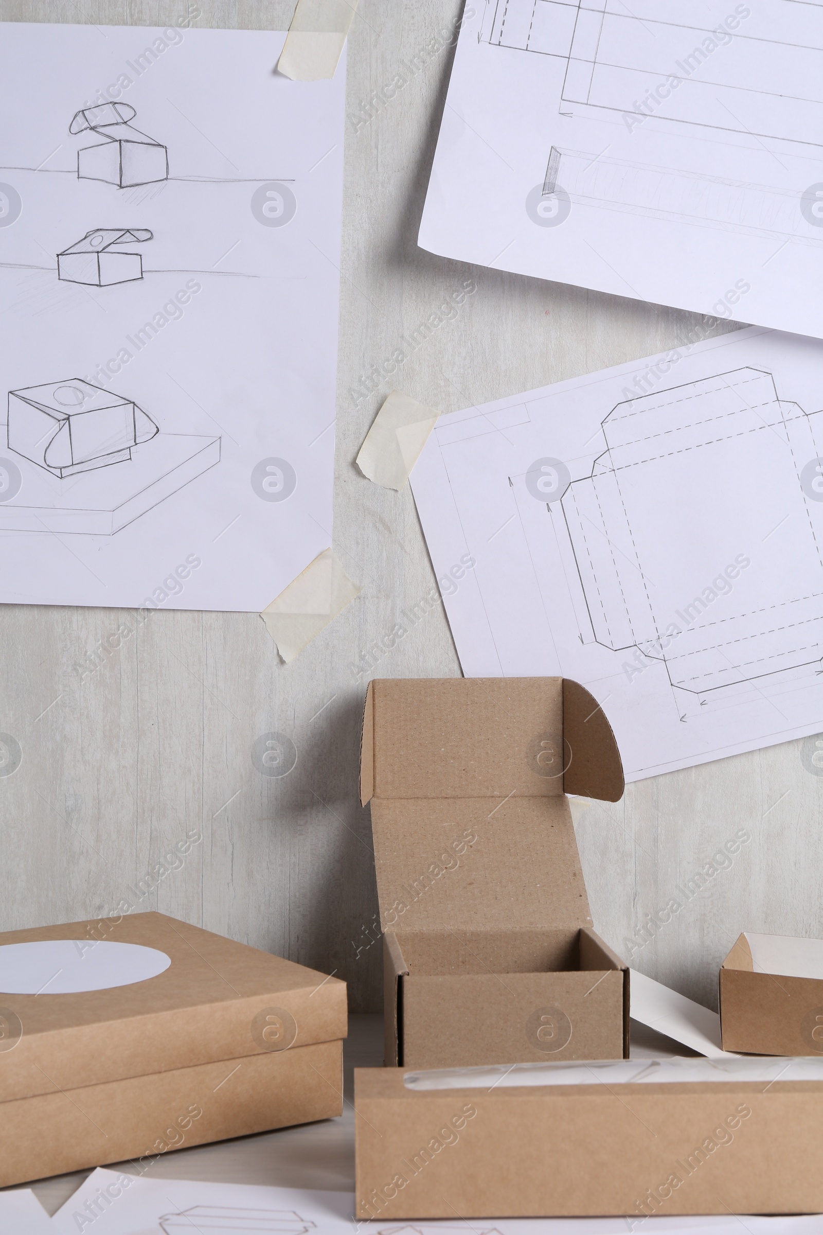 Photo of Creating packaging design. Drawings and boxes on table, closeup