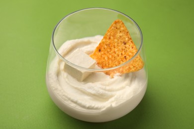 Delicious tofu sauce served with nachos chip on green background, closeup