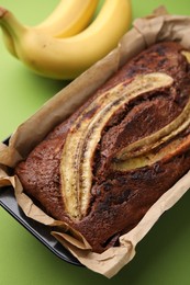 Photo of Delicious banana bread and fresh fruits on green background, closeup
