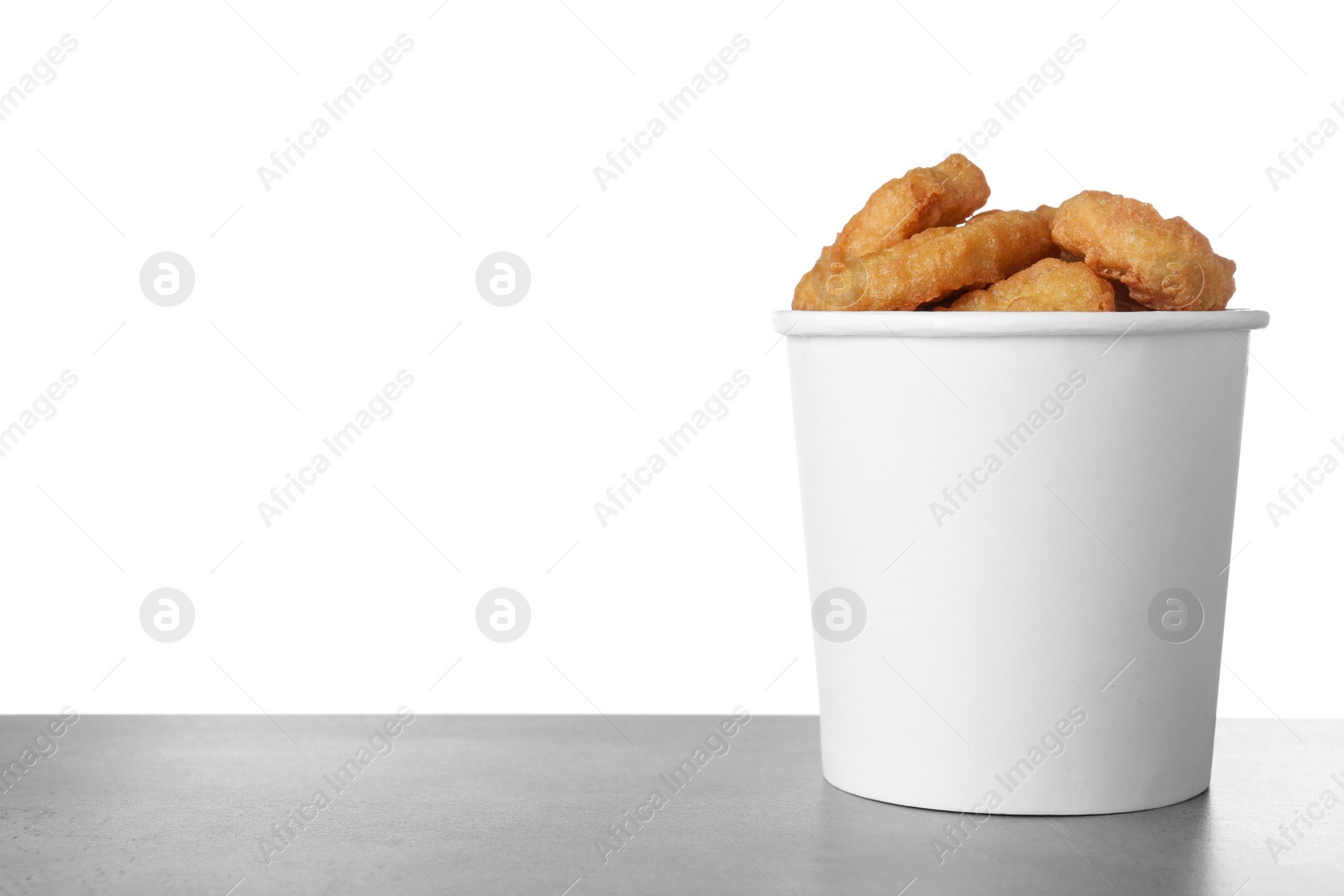Photo of Bucket with tasty chicken nuggets on grey table against white background
