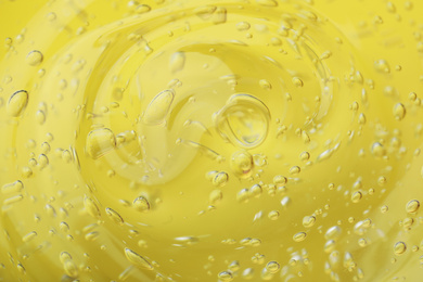 Photo of Pure transparent cosmetic gel on yellow background, closeup