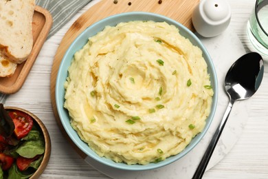 Photo of Bowl of tasty mashed potatoes with onion served on white wooden table, flat lay