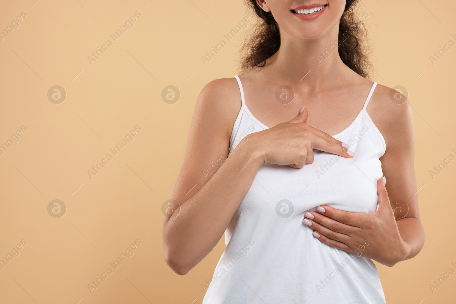 Photo of Woman doing breast self-examination on light brown background, closeup. Space for text