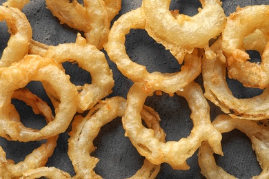 Delicious golden breaded and deep fried crispy onion rings on gray background, closeup