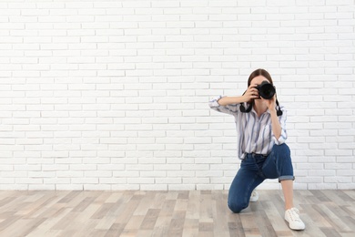 Photo of Professional photographer taking picture near white brick wall. Space for text