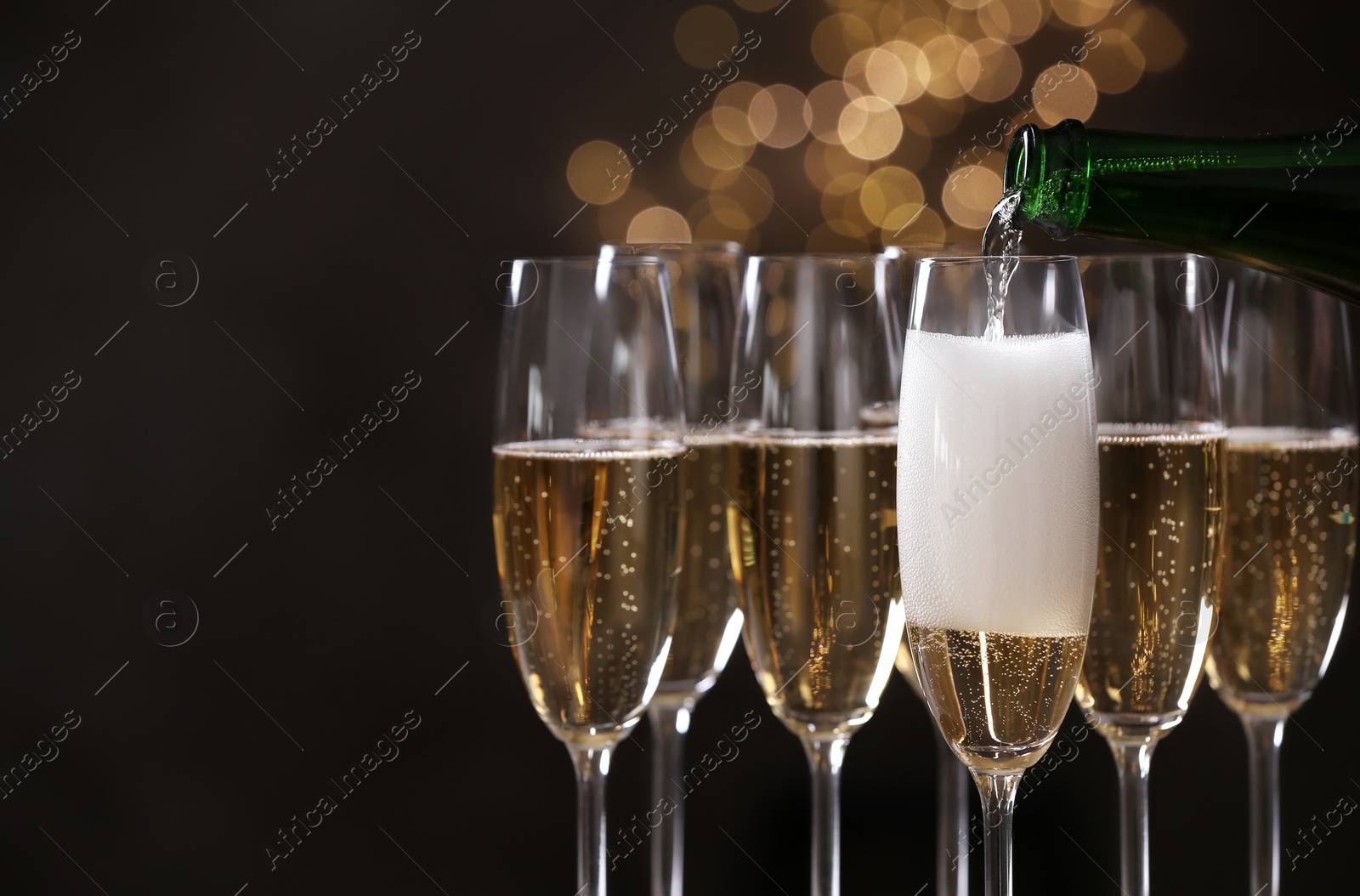 Photo of Pouring champagne into glasses on blurred background, closeup. Space for text