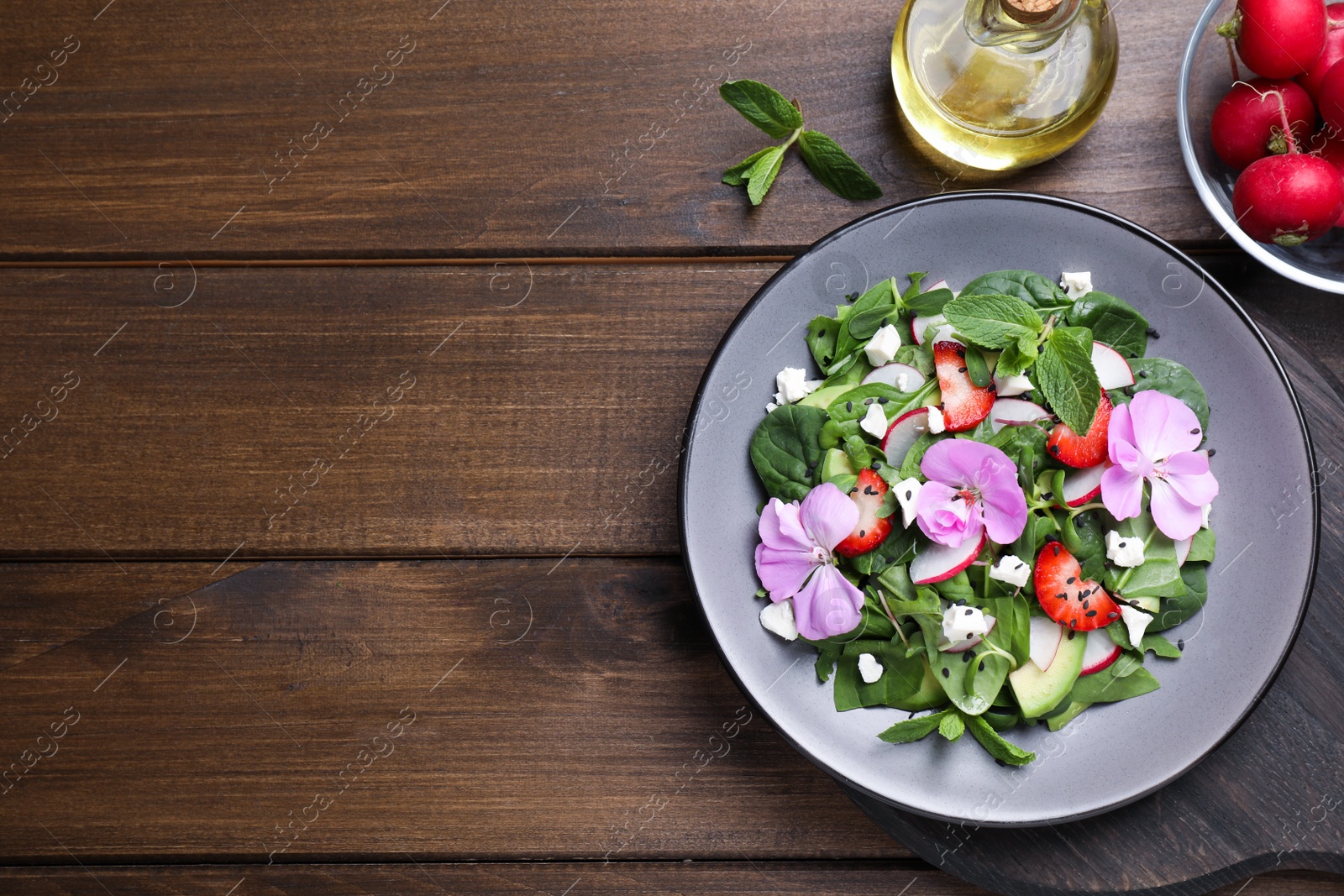 Photo of Fresh spring salad with flowers served on wooden table, flat lay. Space for text