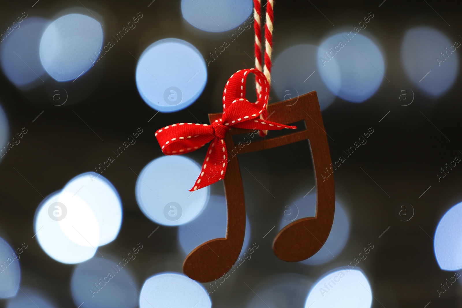 Photo of Wooden music notes against blurred Christmas lights
