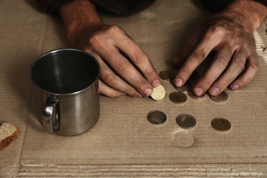 Photo of Poor homeless man counting coins on floor, focus on hands