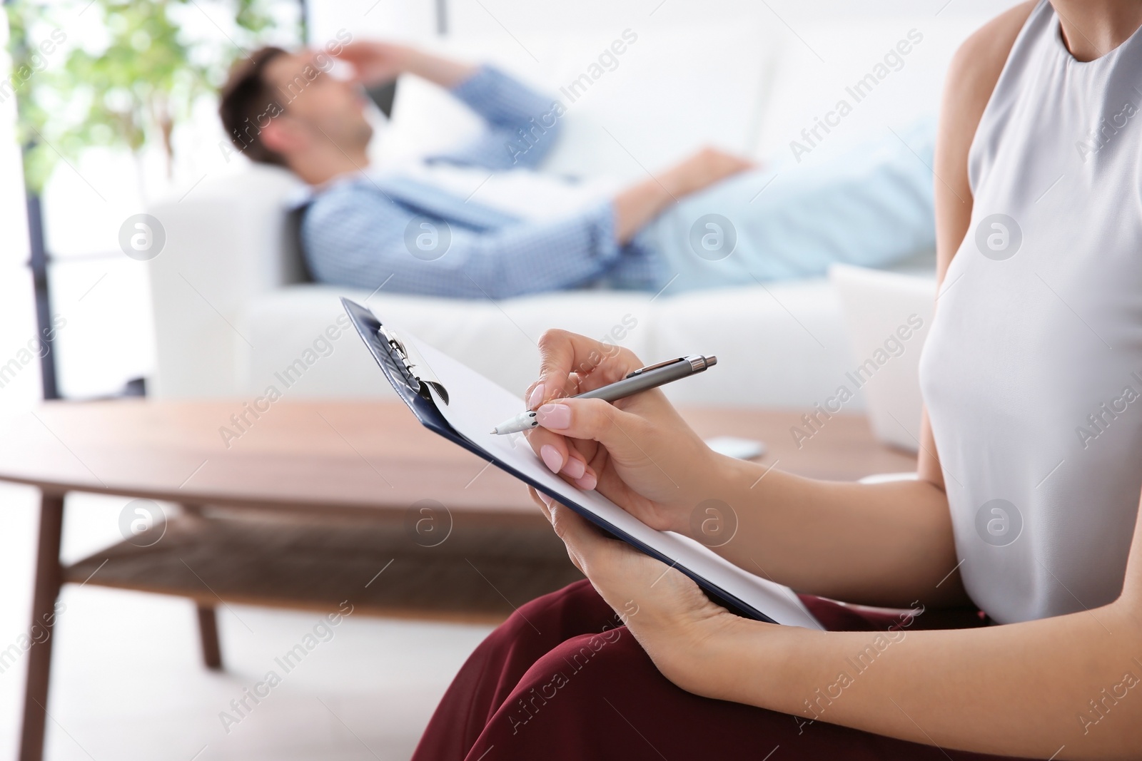 Photo of Female psychologist taking notes on clipboard during appointment with patient. Depression treatment