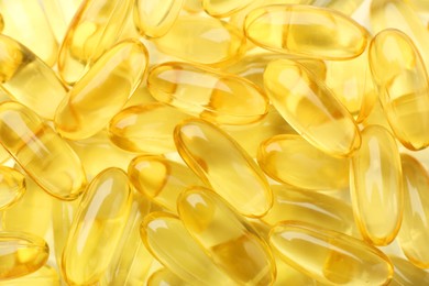 Photo of Yellow vitamin capsules as background, top view