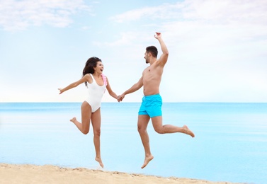 Happy young couple having fun together on beach near sea