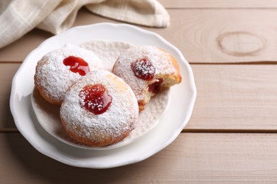 Photo of Hanukkah donuts with jelly and powdered sugar on wooden table, space for text