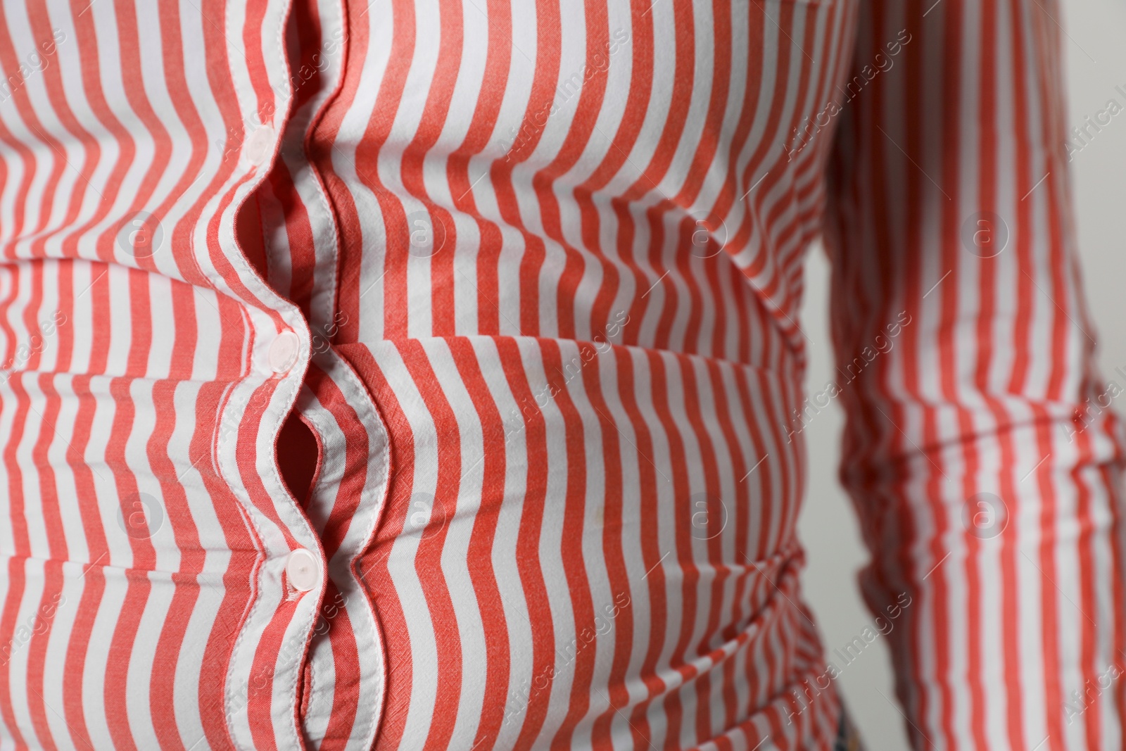 Photo of Overweight woman in tight shirt on grey background, closeup