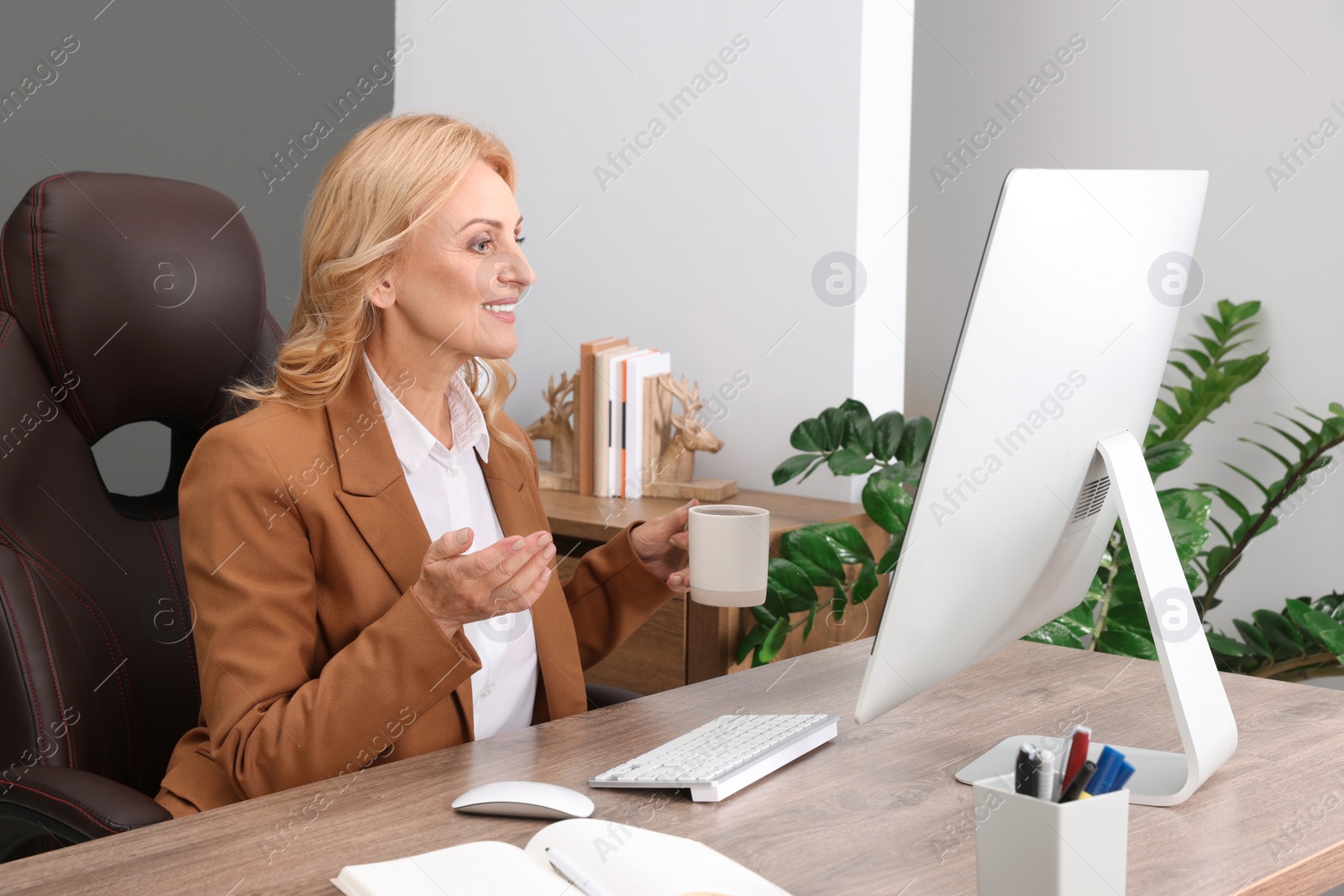 Photo of Lady boss with cup of drink near computer at desk in office. Successful businesswoman