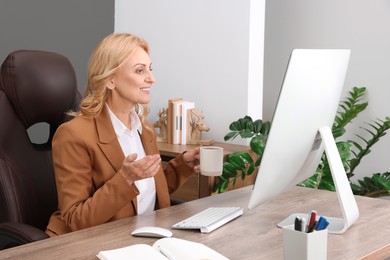 Photo of Lady boss with cup of drink near computer at desk in office. Successful businesswoman