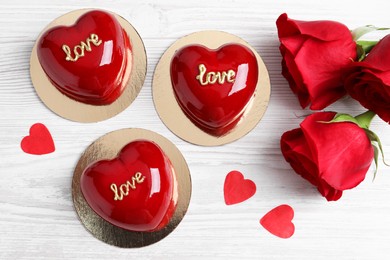 St. Valentine's Day. Delicious heart shaped cakes and roses on white wooden table, flat lay