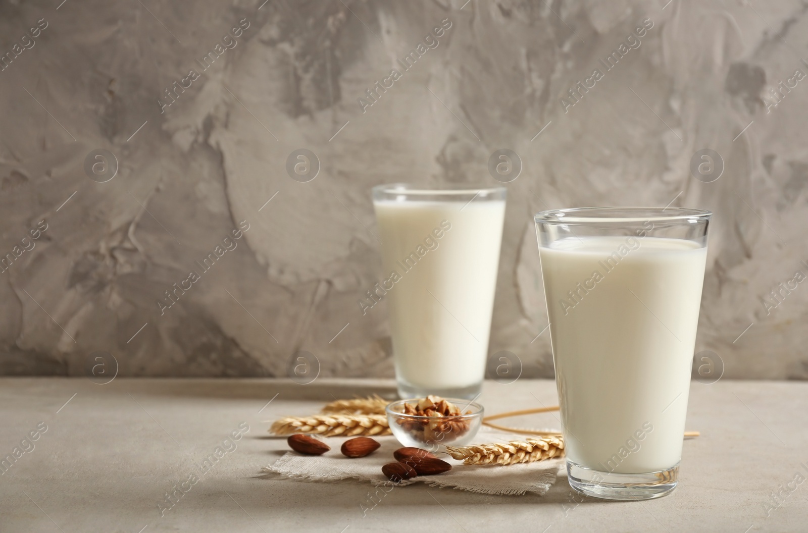 Photo of Glasses with milk and nuts on table