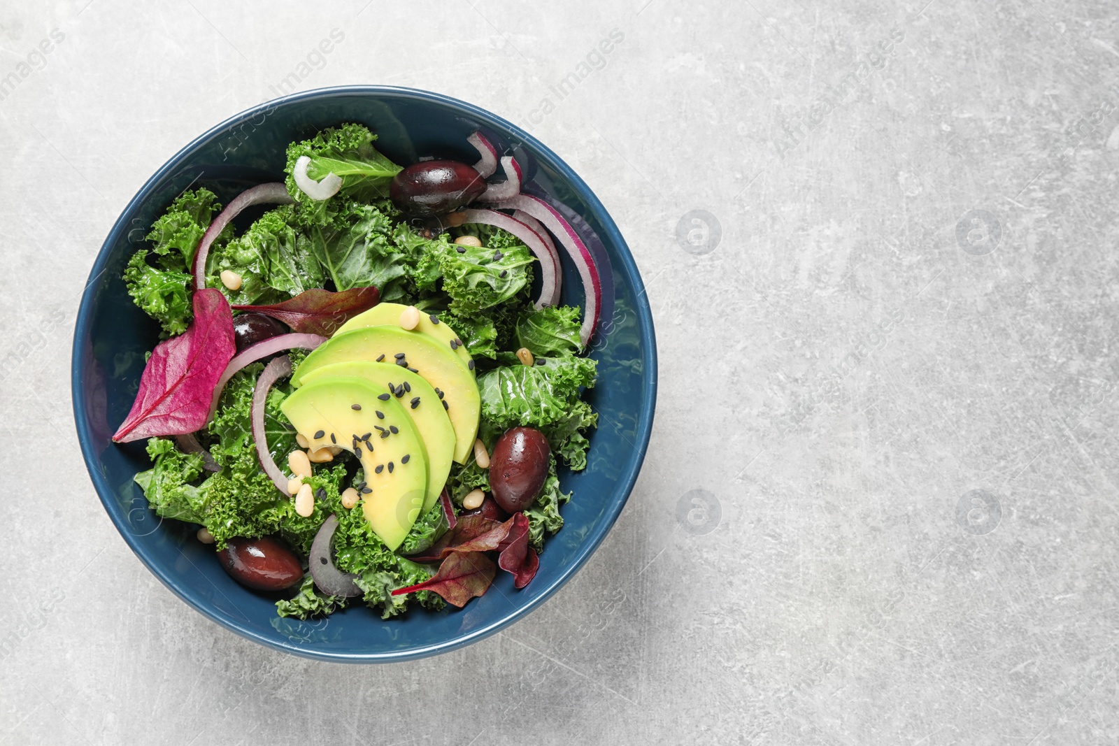 Photo of Tasty fresh kale salad on light grey table, top view. Space for text