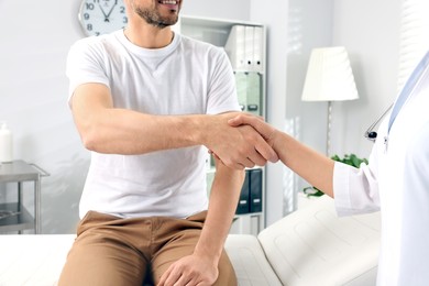 Photo of Doctor shaking hands with patient in clinic, closeup