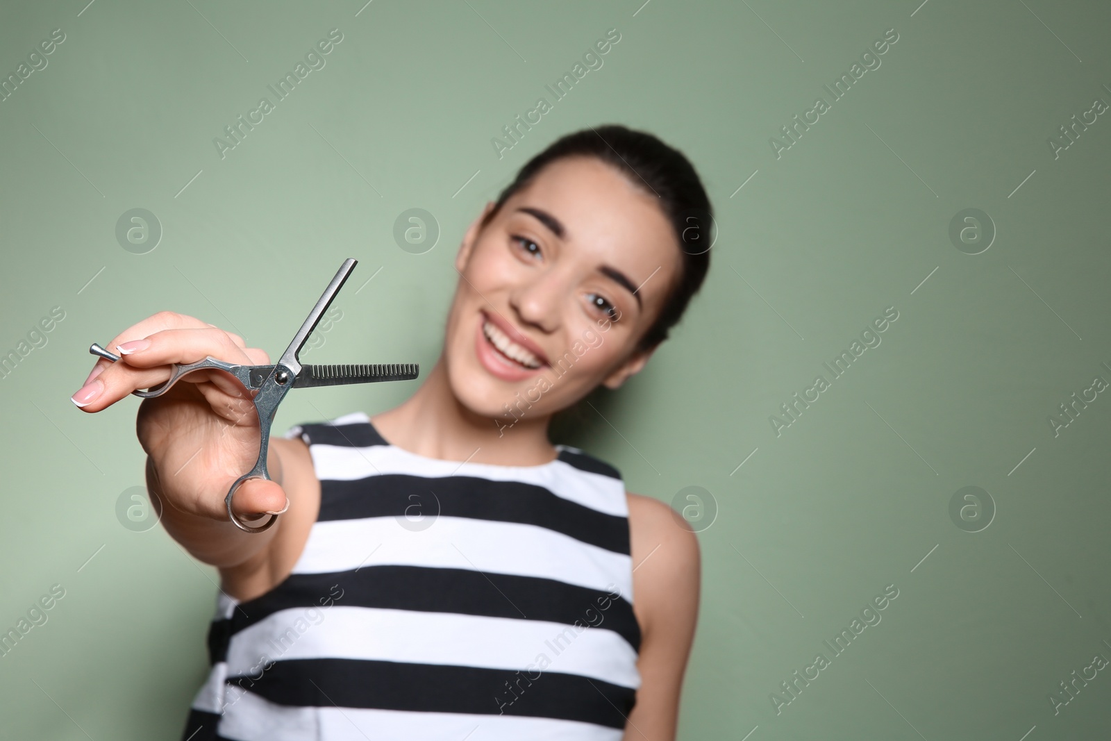 Photo of Professional hairdresser with scissors on color background