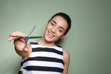 Professional hairdresser with scissors on color background