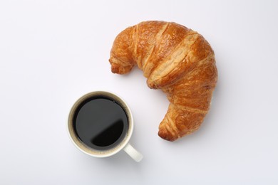 Delicious fresh croissant and cup of coffee on white background, flat lay