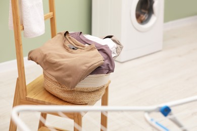 Laundry basket filled with clothes on chair in bathroom. Space for text