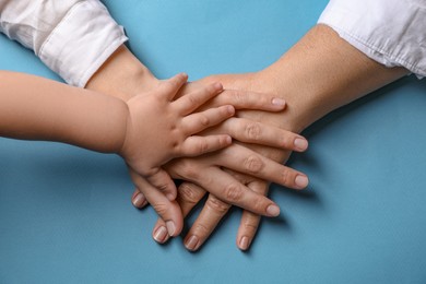Photo of Family holding hands together on light blue background, top view