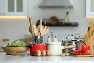 Photo of Set of cooking utensils and products on white table in kitchen