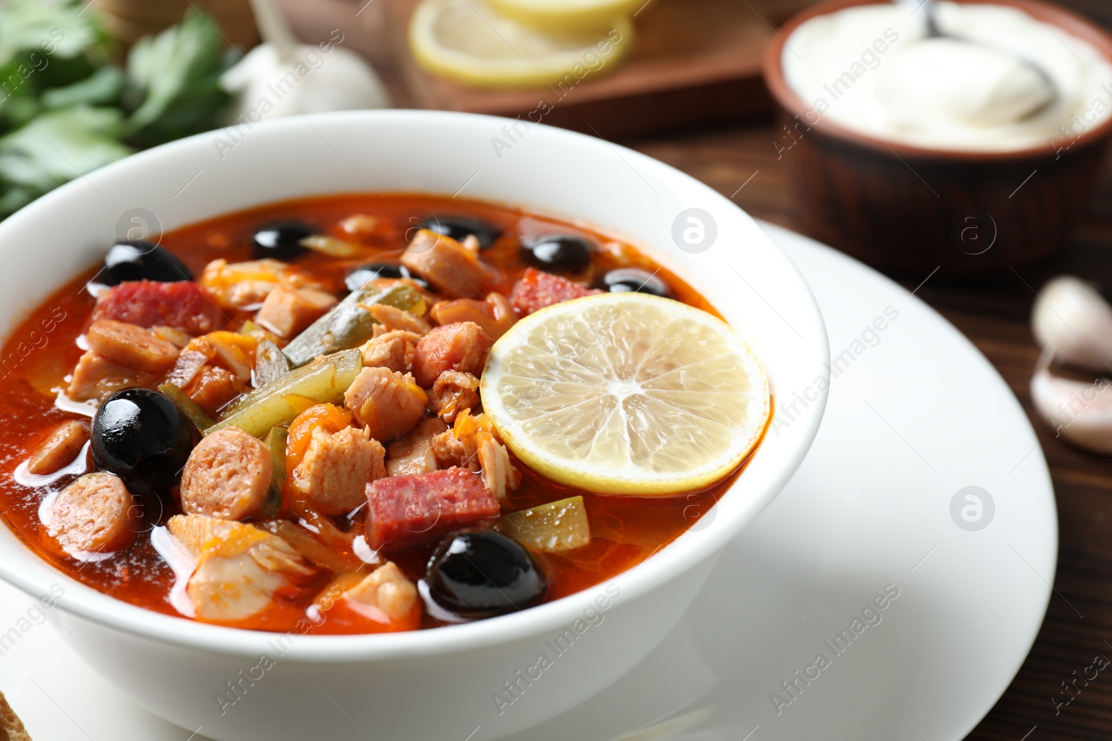 Photo of Meat solyanka soup with sausages, olives and vegetables on table, closeup