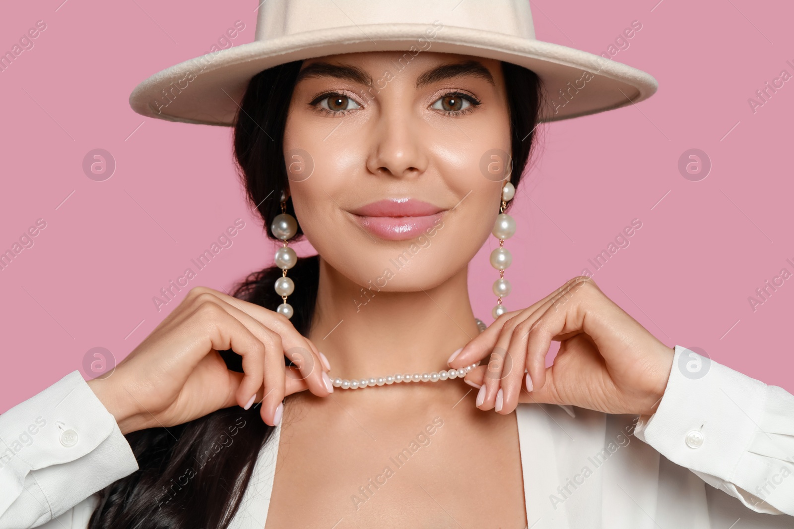 Photo of Young woman wearing elegant pearl jewelry on pink background