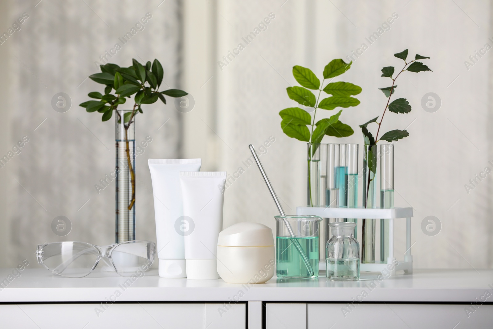 Photo of Many containers and glass tubes with leaves on white lab drawer indoors