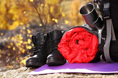 Photo of Set of camping equipment with sleeping bag on ground outdoors