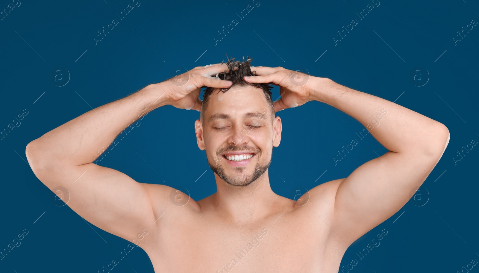 Photo of Handsome man washing hair on blue background