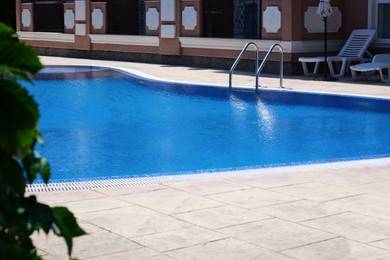 Outdoor swimming pool with handrails at resort on sunny day