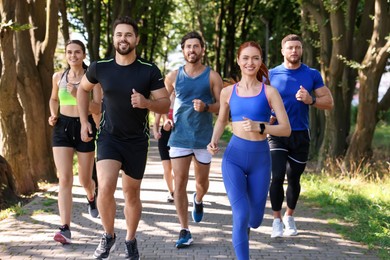 Group of people running in park on sunny day