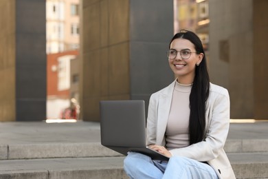 Photo of Happy young woman using modern laptop outdoors. Space for text