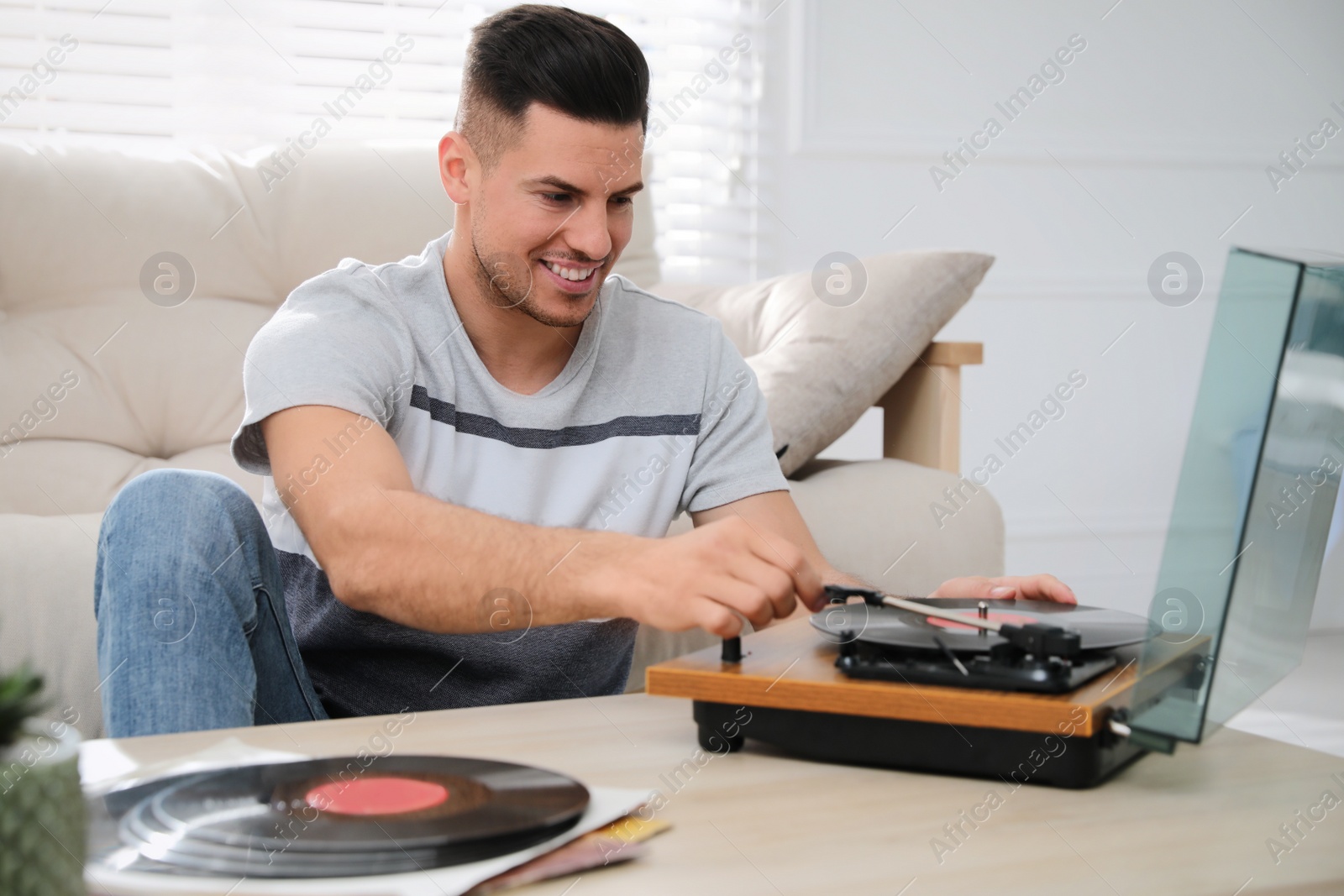 Photo of Happy man listening to music with turntable at home