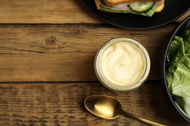 Flat lay composition with jar of delicious mayonnaise on wooden table. Space for text