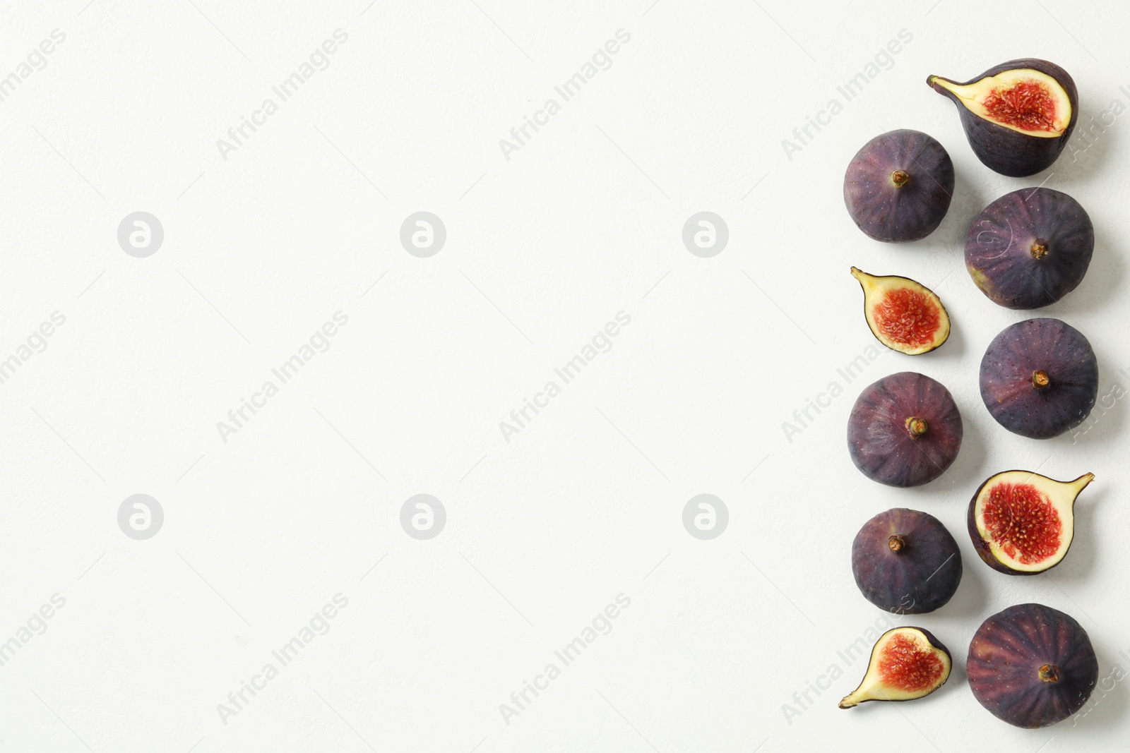 Photo of Whole and cut tasty fresh figs on white table, flat lay. Space for text