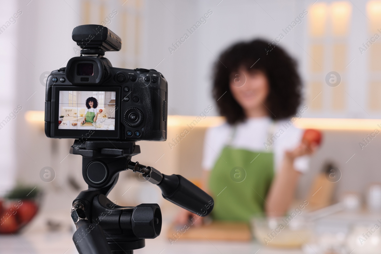 Photo of Food blogger recording video in kitchen, focus on camera