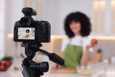 Food blogger recording video in kitchen, focus on camera