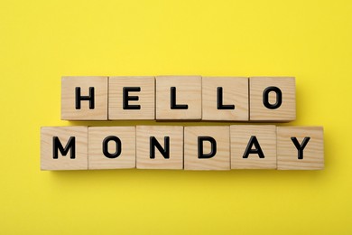 Photo of Wooden cubes with message Hello Monday on yellow background, flat lay